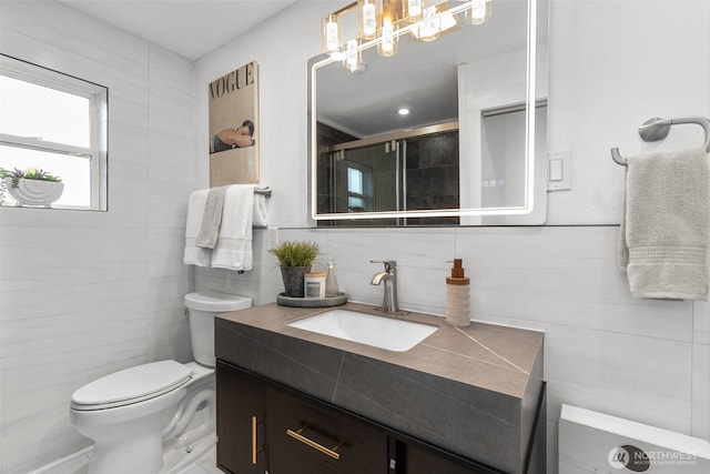 full bathroom featuring toilet, a stall shower, tile walls, and vanity