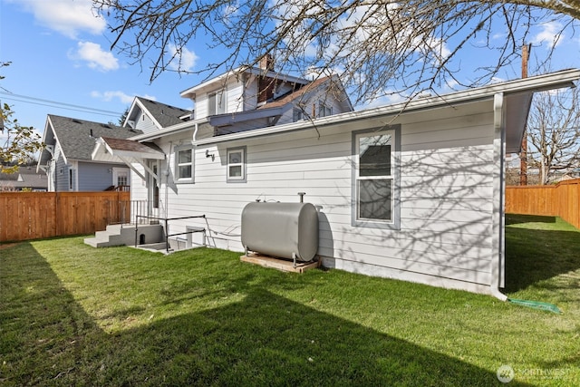 back of house with a yard, a chimney, fence, and heating fuel