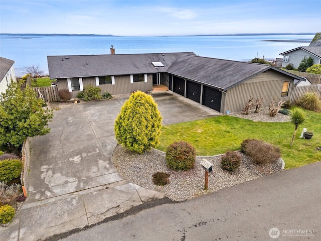 single story home featuring a water view, a front yard, fence, a garage, and driveway