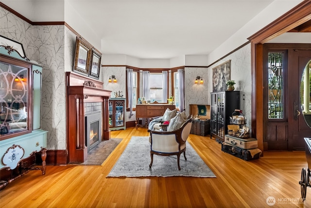 living room featuring a fireplace with flush hearth, light wood-style flooring, and wallpapered walls