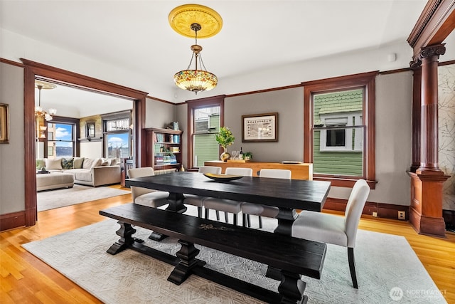 dining area featuring light wood finished floors, decorative columns, and a wealth of natural light