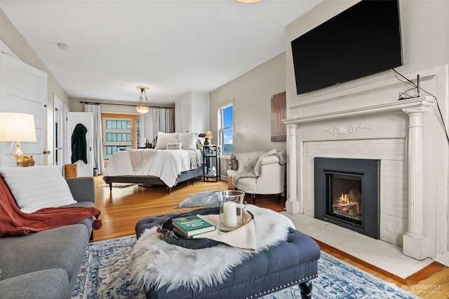 bedroom with a brick fireplace, multiple windows, and wood finished floors