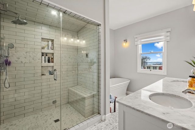 bathroom with double vanity, a stall shower, a freestanding bath, and a sink