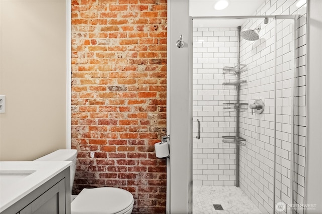 full bathroom featuring brick wall, a stall shower, vanity, and toilet