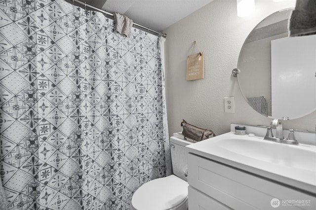 full bathroom featuring a textured wall, vanity, and toilet