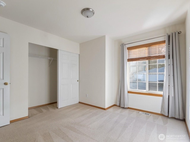 unfurnished bedroom with visible vents, baseboards, light colored carpet, and a closet