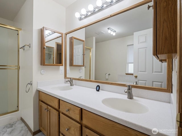 full bath with a sink, a shower with door, and double vanity