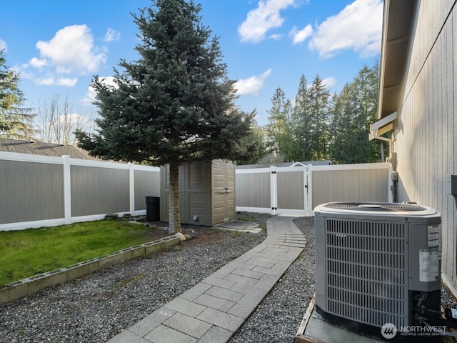 view of yard featuring central AC unit, a fenced backyard, and a gate