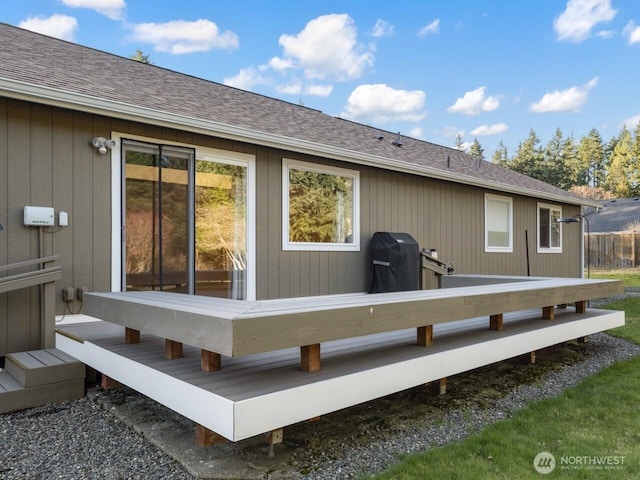 rear view of property featuring a deck and roof with shingles