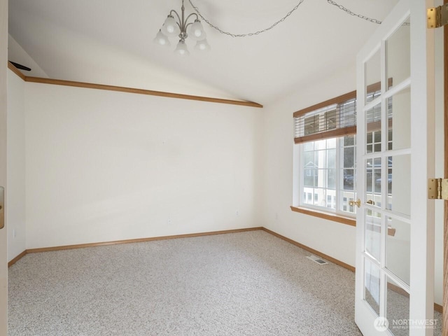 carpeted empty room with visible vents, baseboards, a notable chandelier, and vaulted ceiling