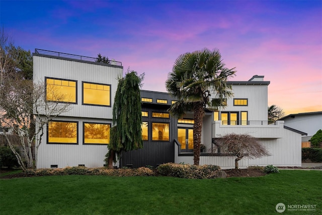 back of house at dusk featuring crawl space and a yard