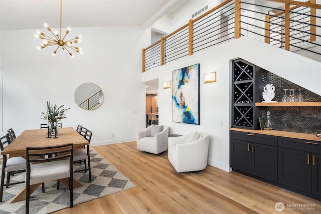 dining room with high vaulted ceiling, baseboards, light wood-type flooring, and a chandelier