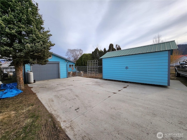 detached garage featuring concrete driveway and fence