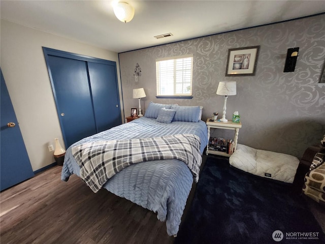 bedroom with wood finished floors, visible vents, and a closet