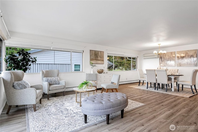 living area with light wood-type flooring, an inviting chandelier, baseboard heating, and an AC wall unit