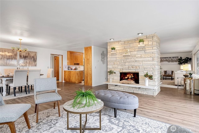 living room with an inviting chandelier, a fireplace, and wood finished floors