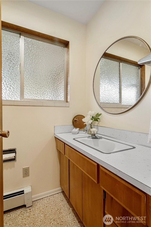 bathroom with a baseboard heating unit, vanity, baseboards, and speckled floor