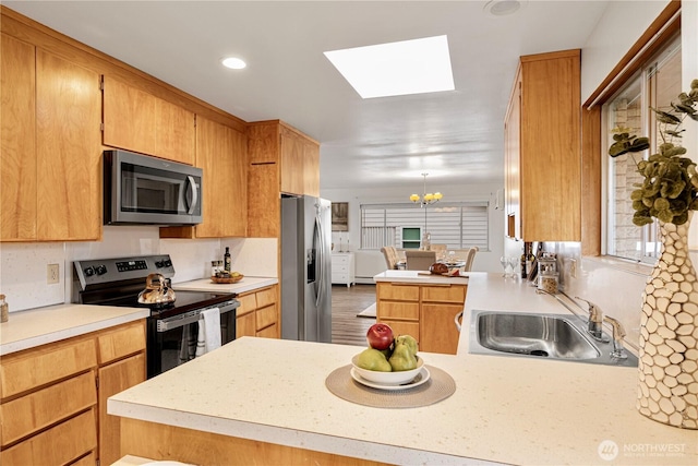 kitchen featuring stainless steel appliances, a peninsula, a sink, and light countertops