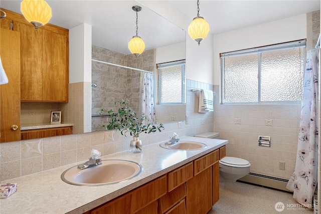 bathroom featuring toilet, tile walls, baseboard heating, and a sink