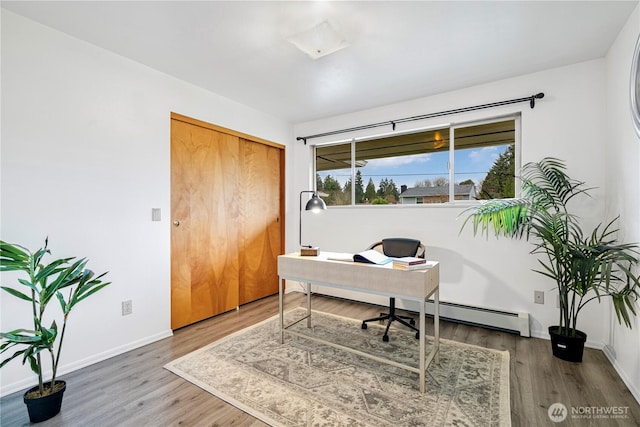 office area with a baseboard heating unit, baseboards, and wood finished floors