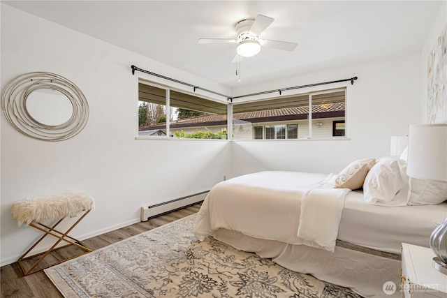 bedroom featuring a baseboard radiator, wood finished floors, a ceiling fan, and baseboards