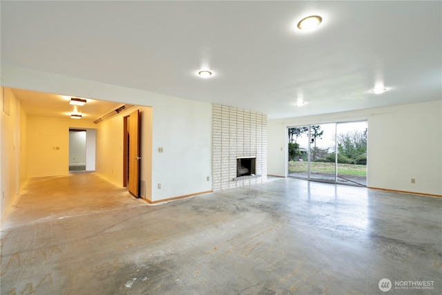 unfurnished living room featuring finished concrete floors, a fireplace, and baseboards