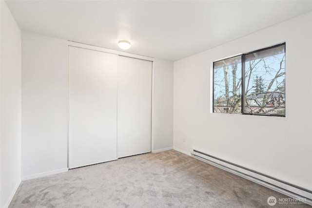 unfurnished bedroom with a closet, baseboards, baseboard heating, and carpet flooring