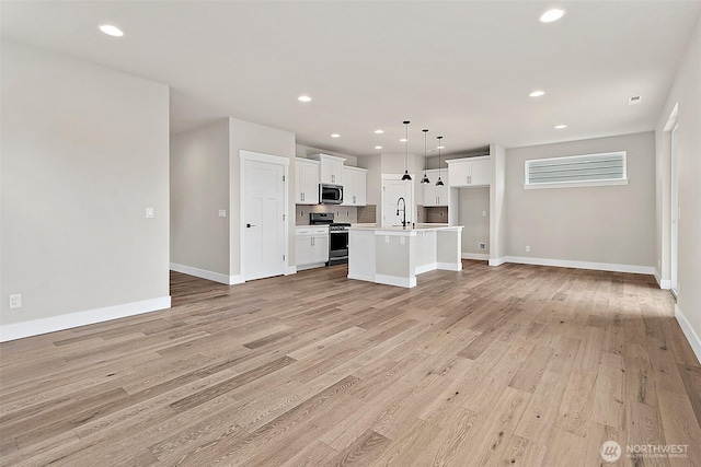 unfurnished living room featuring recessed lighting, baseboards, a sink, and light wood finished floors