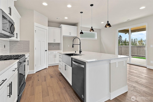 kitchen featuring stainless steel appliances, white cabinetry, a sink, and light wood finished floors