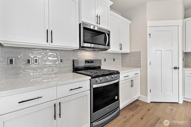 kitchen featuring appliances with stainless steel finishes, decorative backsplash, white cabinets, and light wood-style floors