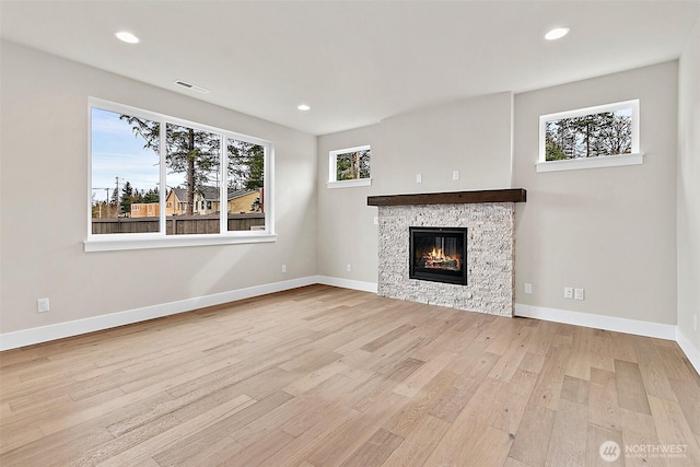 unfurnished living room featuring baseboards, a stone fireplace, wood finished floors, and recessed lighting