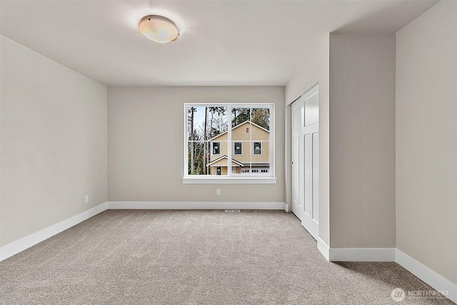 unfurnished room featuring carpet and baseboards