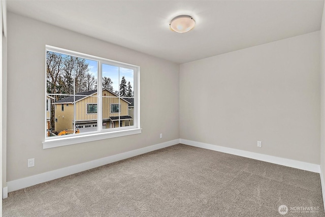 spare room featuring carpet and baseboards