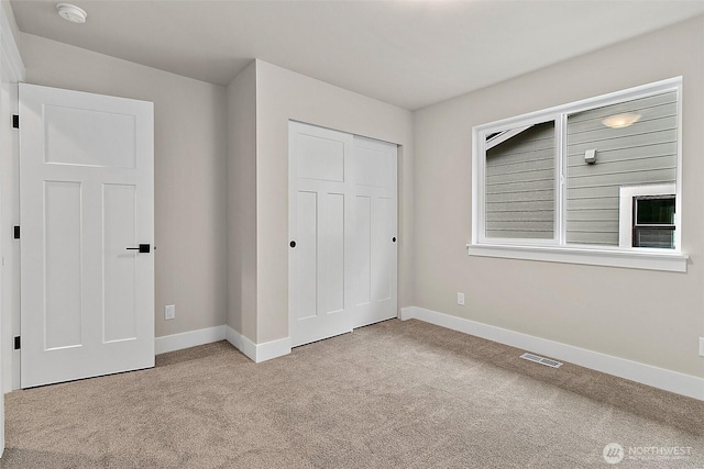 unfurnished bedroom with a closet, baseboards, visible vents, and carpet flooring