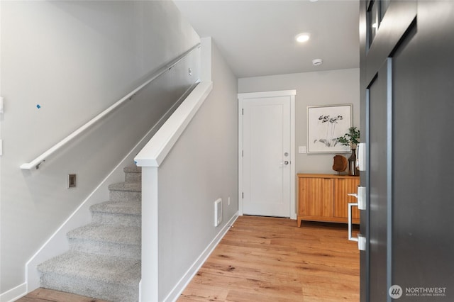 entryway with light wood finished floors, baseboards, stairs, and visible vents