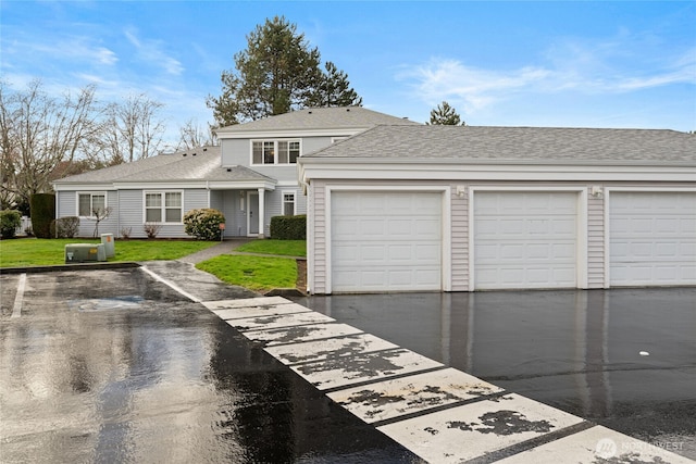 traditional home with a front lawn, roof with shingles, and community garages