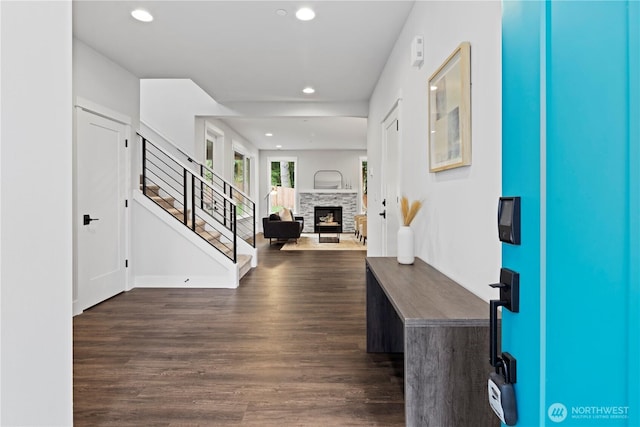 entrance foyer with dark wood-type flooring, recessed lighting, a stone fireplace, and stairway