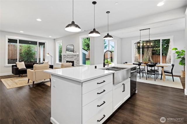 kitchen with a fireplace, a sink, light countertops, dark wood-style floors, and pendant lighting