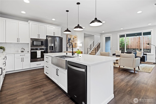 kitchen with light countertops, decorative backsplash, appliances with stainless steel finishes, dark wood-type flooring, and a sink