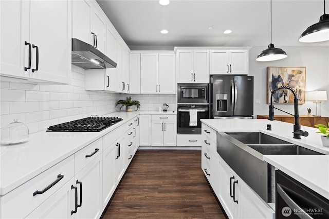 kitchen featuring decorative backsplash, stainless steel appliances, light countertops, under cabinet range hood, and a sink