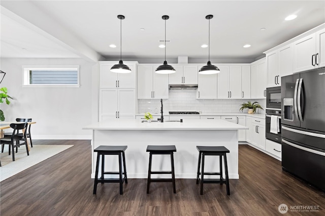 kitchen featuring under cabinet range hood, a breakfast bar, a sink, light countertops, and black appliances