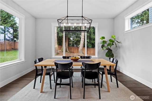 dining room featuring dark wood-style flooring, baseboards, and an inviting chandelier