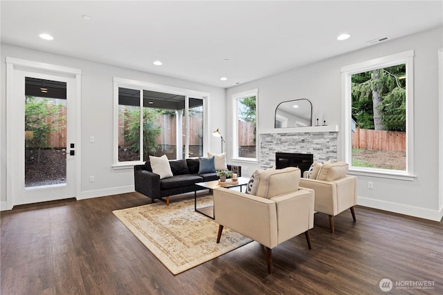 living area featuring recessed lighting, dark wood-style flooring, visible vents, and a fireplace