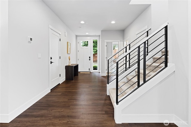 foyer featuring baseboards, stairway, and dark wood-style flooring