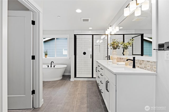 full bath with a sink, visible vents, a soaking tub, double vanity, and a stall shower