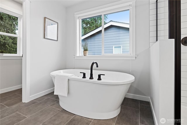 full bathroom with a freestanding bath and baseboards