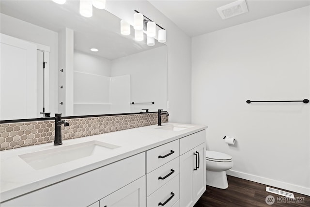 bathroom featuring toilet, visible vents, a sink, and wood finished floors