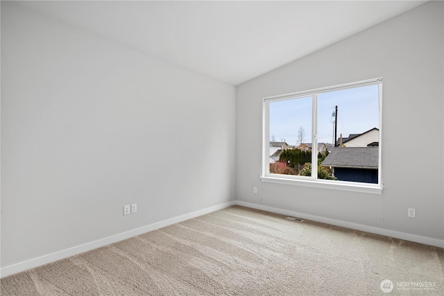 carpeted empty room with vaulted ceiling, visible vents, and baseboards