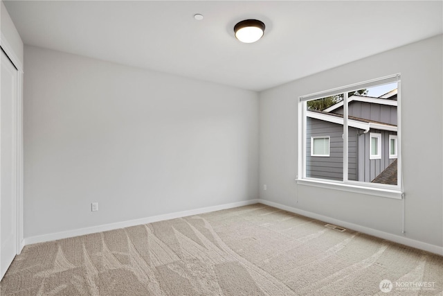 spare room featuring carpet flooring, visible vents, and baseboards