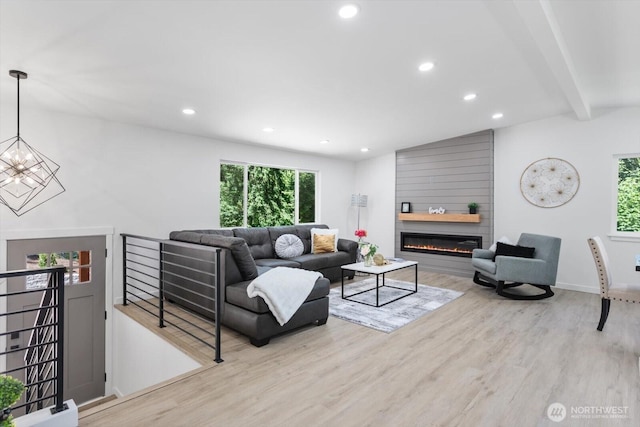 living area with recessed lighting, a large fireplace, wood finished floors, baseboards, and an inviting chandelier